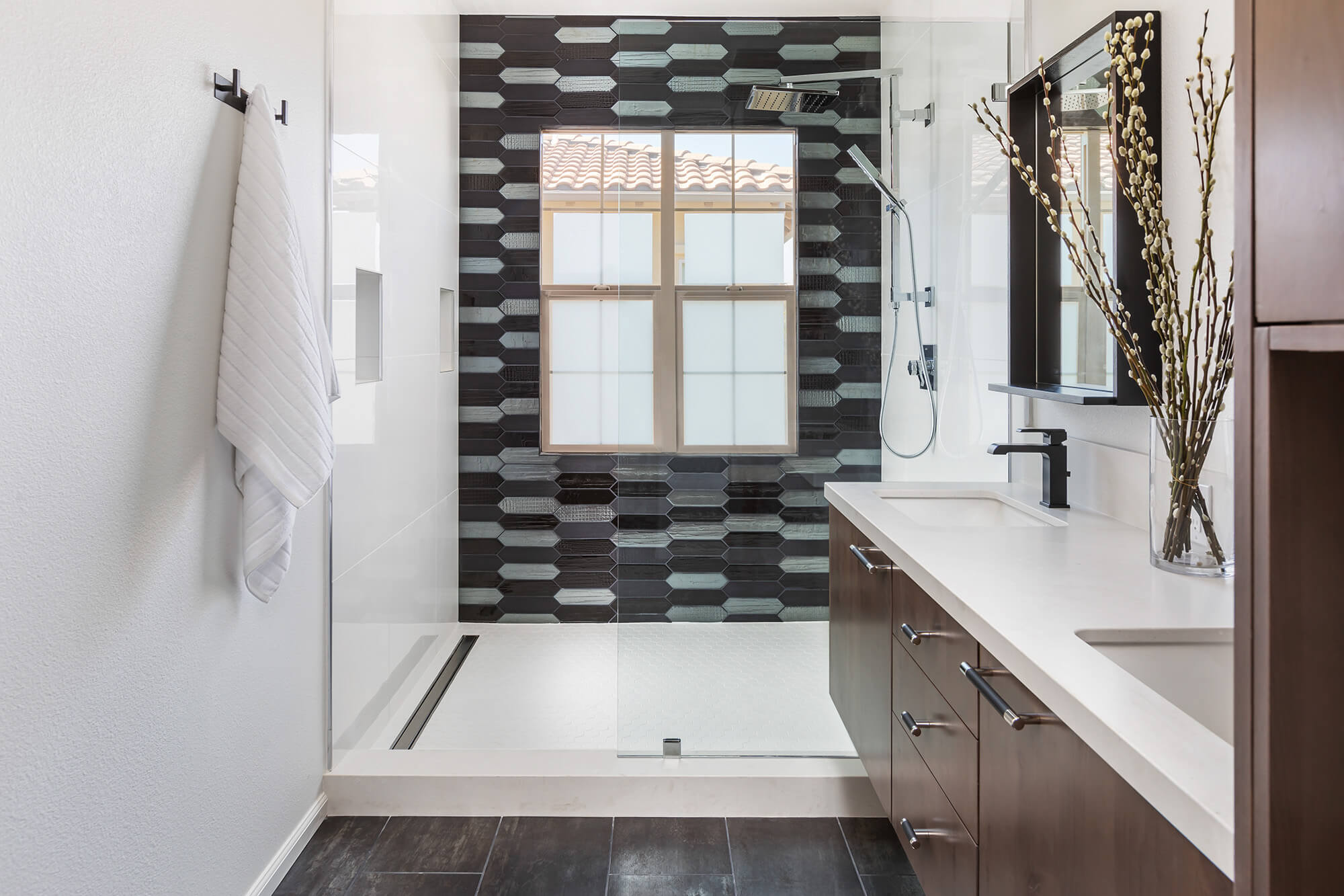 a renovated shower with black and white tiles