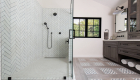 Bathroom renovation with herringbone pattern shower tile and patterned floor insets