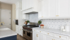 Open concept kitchen remodel with white cabinetry and blue island