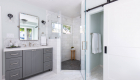 Marble flooring and shower tile with gray cabinetry in bathroom remodel