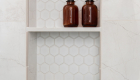 shampoo-niche-Emser-glazed-porcelain-white-hex-backsplash-with-grey-trim-and-quartz-shelves