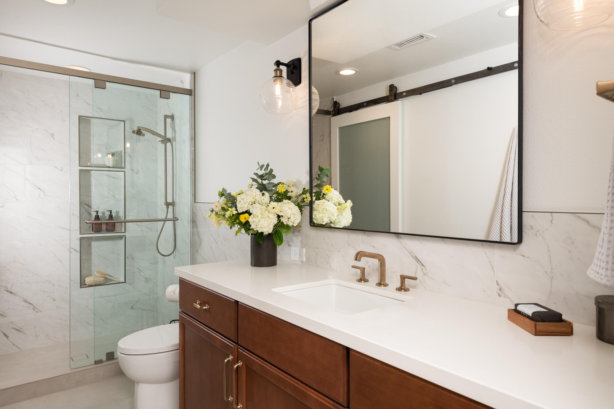 guest-bathroom-in-irvine-with-Emser-porcelain-tile-flooring-in-ivory-matte-and-Sea-Swell-Swing-Arm-Sconces-Black-Antique-brass