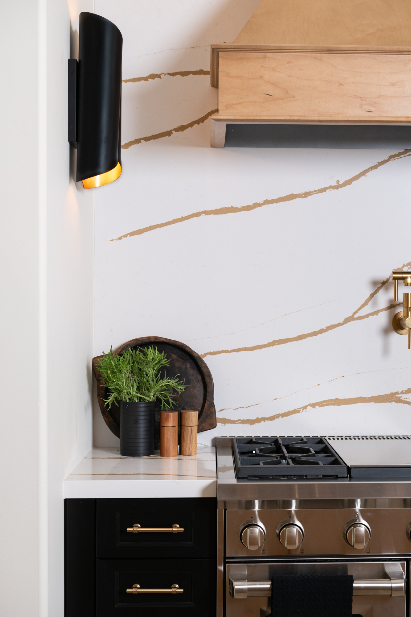 two-black-and-gold-leaf-Kari-sconces-with-dimmers-on-range-wall