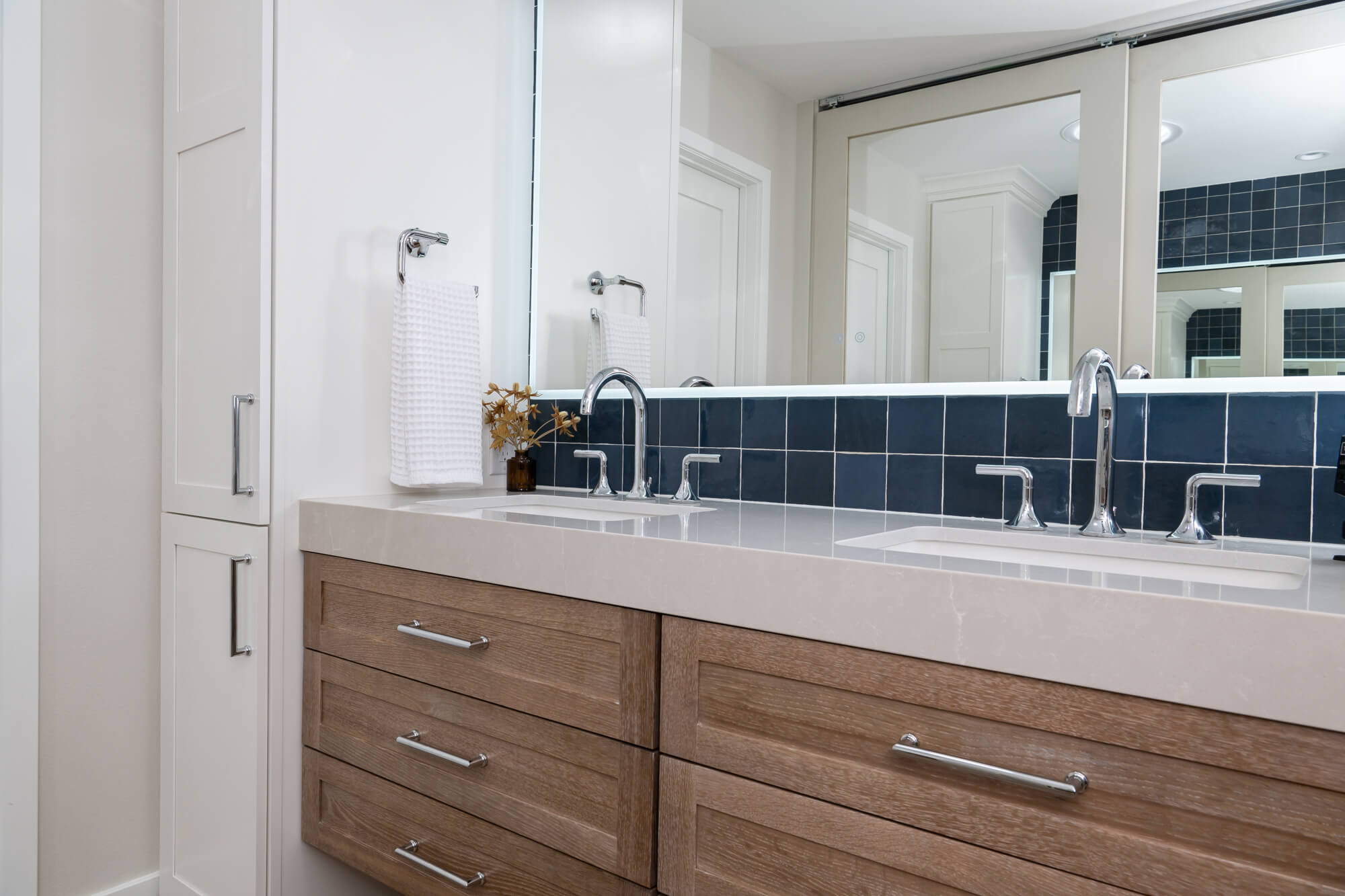 maple-utility-storage-cabinets-by Omega-in-elemental-white-with-polished-chrome-pulls-sit-on-each-side-of-vanity