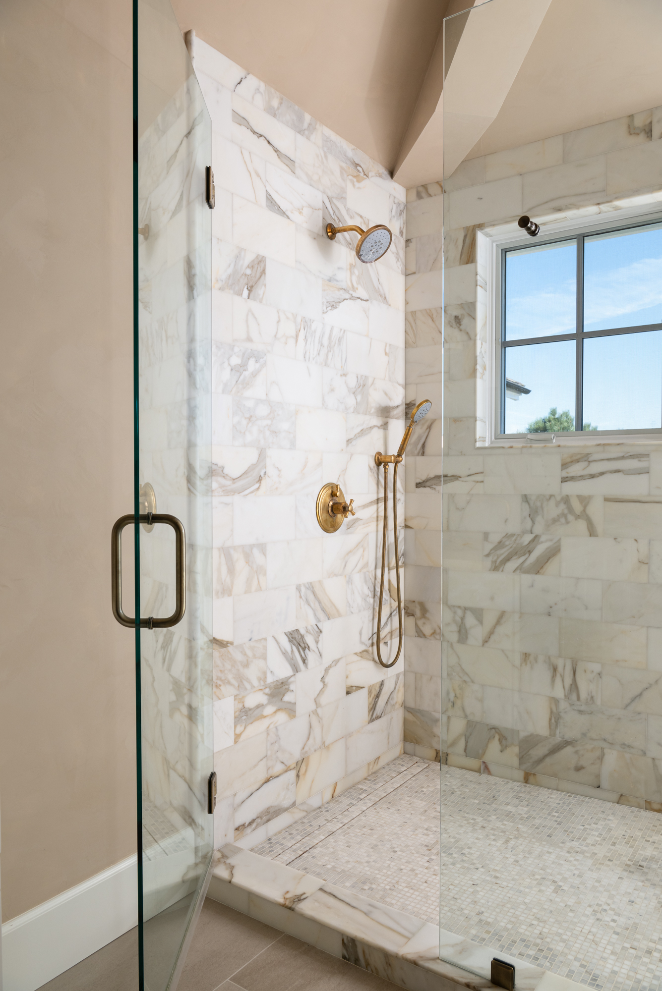 marble-shower-with-antique-brass-shower-fixtures-and-mosaic-flooring-with-linear-drain
