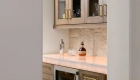 bar-area-includes-an-under-counter-beverage-fridge-and-glass-inserts-in-the-upper-cabinetry