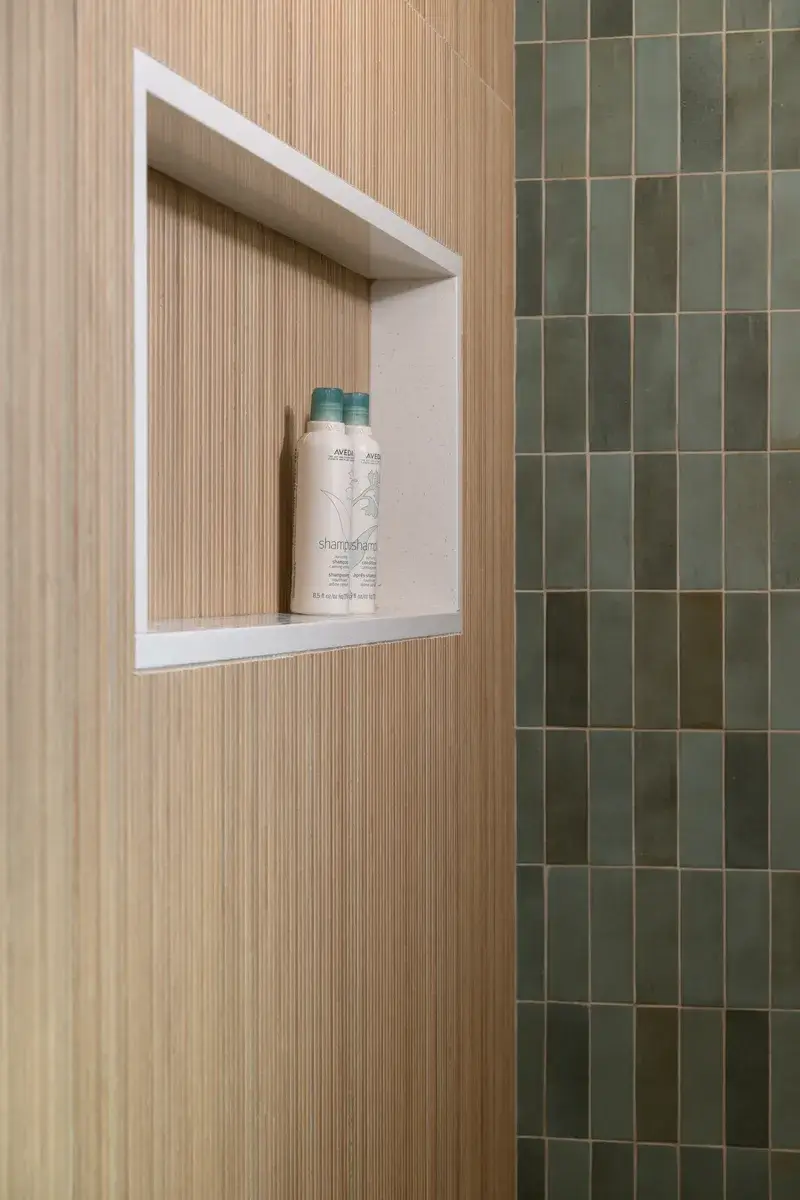 shower-niche-accented-in-white-quartz-trim-and-champagne-bronze-wall-mount-handshower-and-fixed-showerhead-plus-a-celing-mounted-rainshower-head