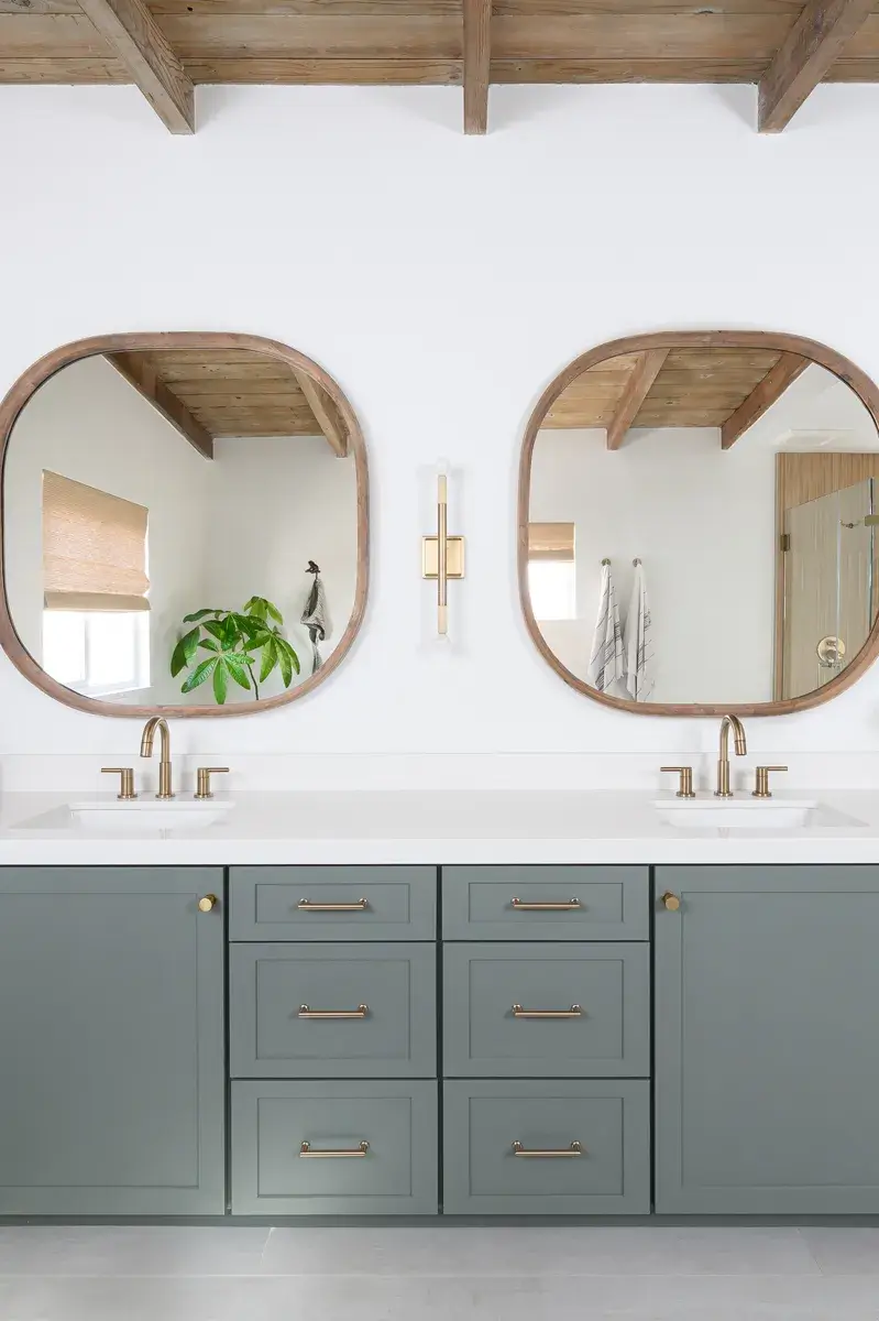 two-wood-framed-mirrors-and-two-champagne-bronze-light-wall-sconces-sit-above-the-vanity