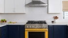 vibrant-yellow-slide-in-gas-range-sits-below-stainless-steel-vent-hood